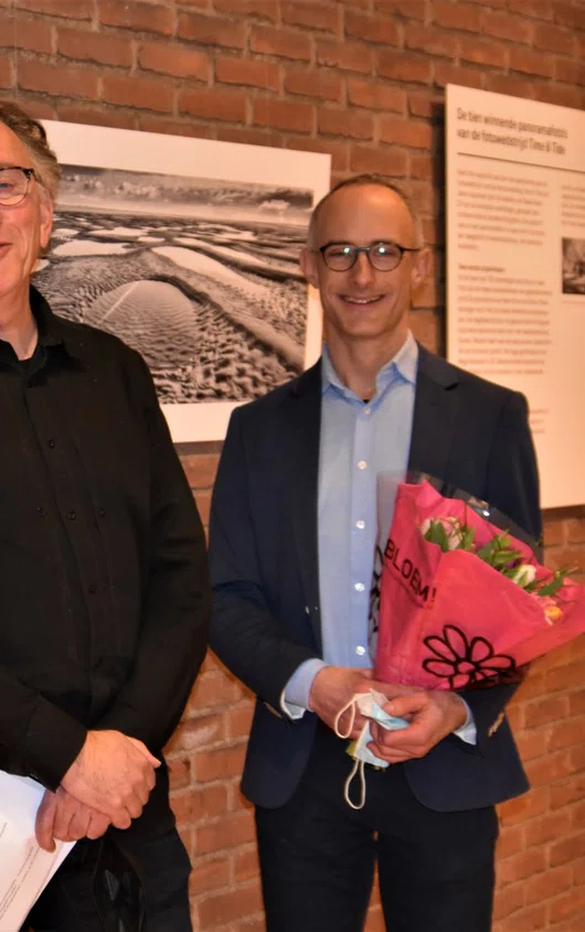 Twee winnaars van de open call met bloemen in de hand en in het midden Siebe Swart.