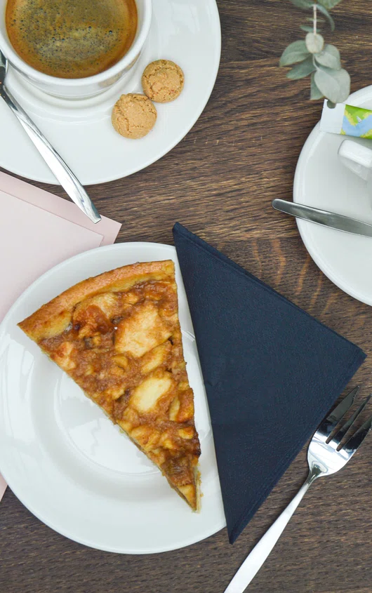 Een tafel met appeltaart, twee kopjes koffie en een menukaart