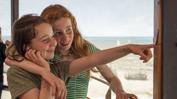 Twee zusjes luisteren naar de audiotour terwijl ze wijzen naar het panorama