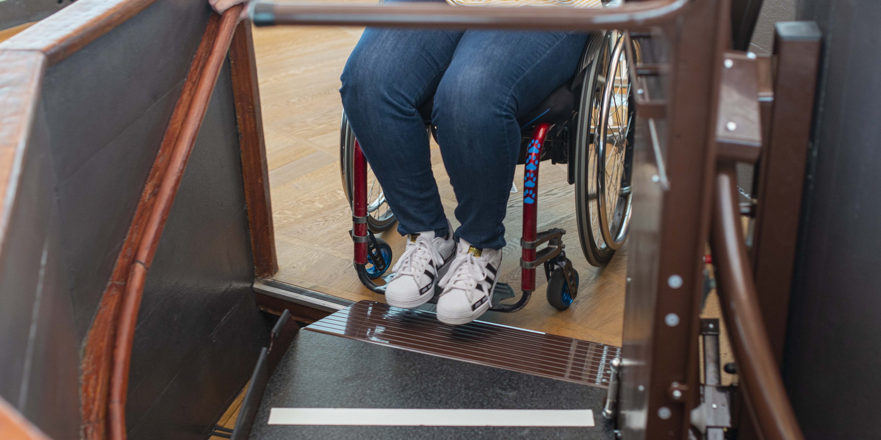 Traplift, een gebruiker in een rolstoel rijdt de plaat van de lift op.