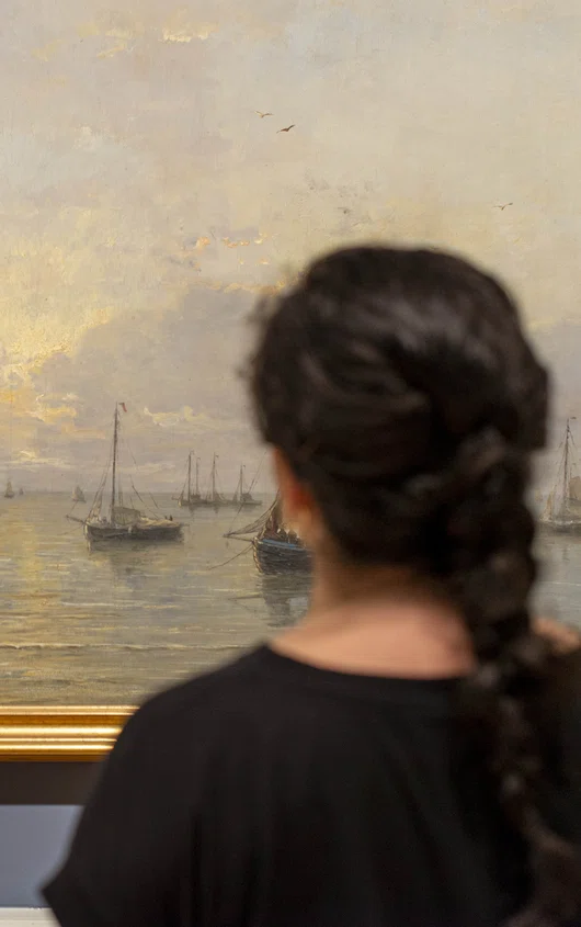 Bezoeker op zaal kijkt naar een kunstwerk uit de collectie.