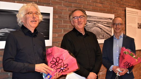Twee winnaars van de open call met bloemen in de hand en in het midden Siebe Swart.
