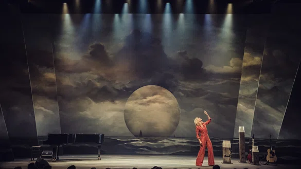 Claudia de Breij in een rood pak op het podium tijdens een voorstelling