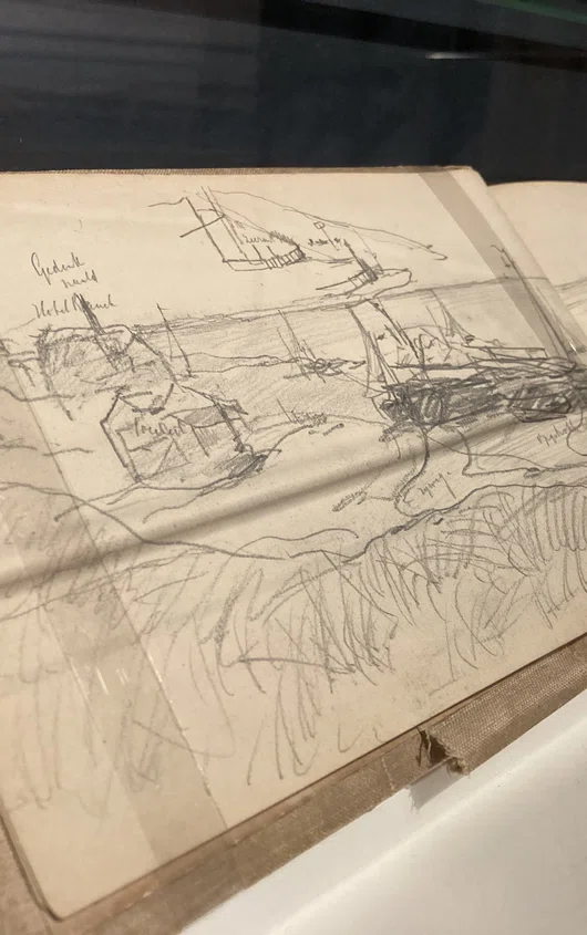 opengeslagen schetsboek met potloodtekening van boten op het strand