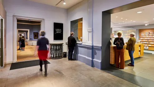 De entreehal van Museum Panorama Mesdag met mensen bij de kassa en in de zalen.